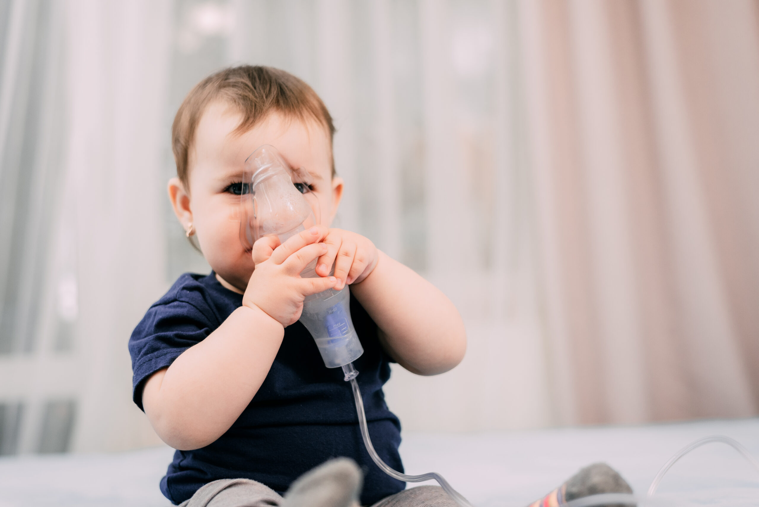 a little girl yourself holding the mask of the nebulizer, making inhalation and treated